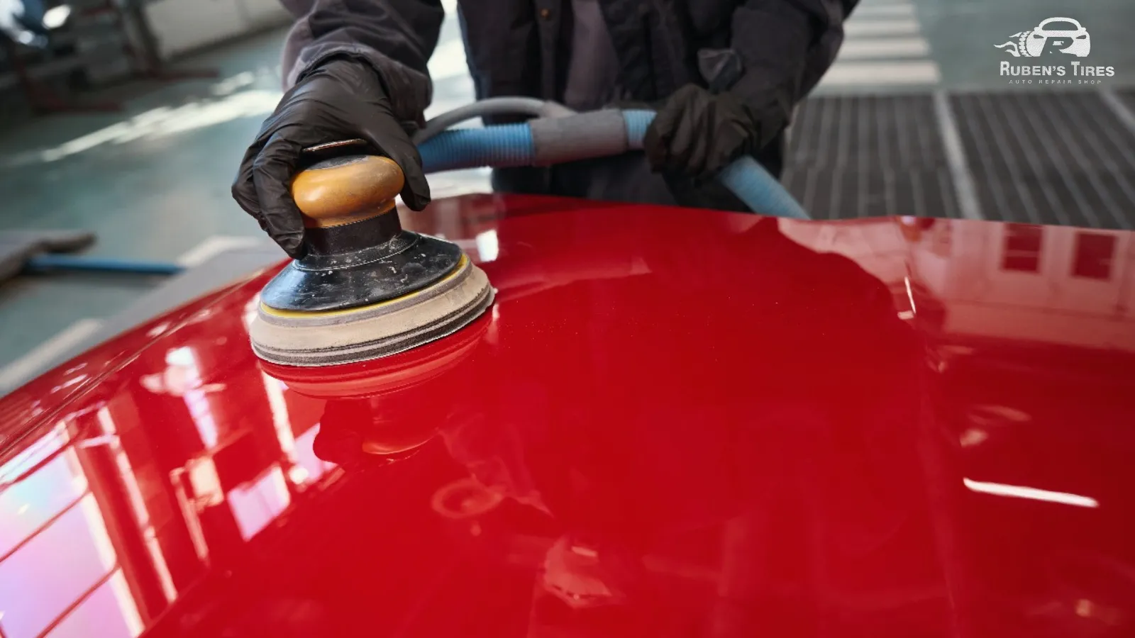 Technician buffing a red car hood for a smooth and polished finish at Ruben's Tires in North Semoran.