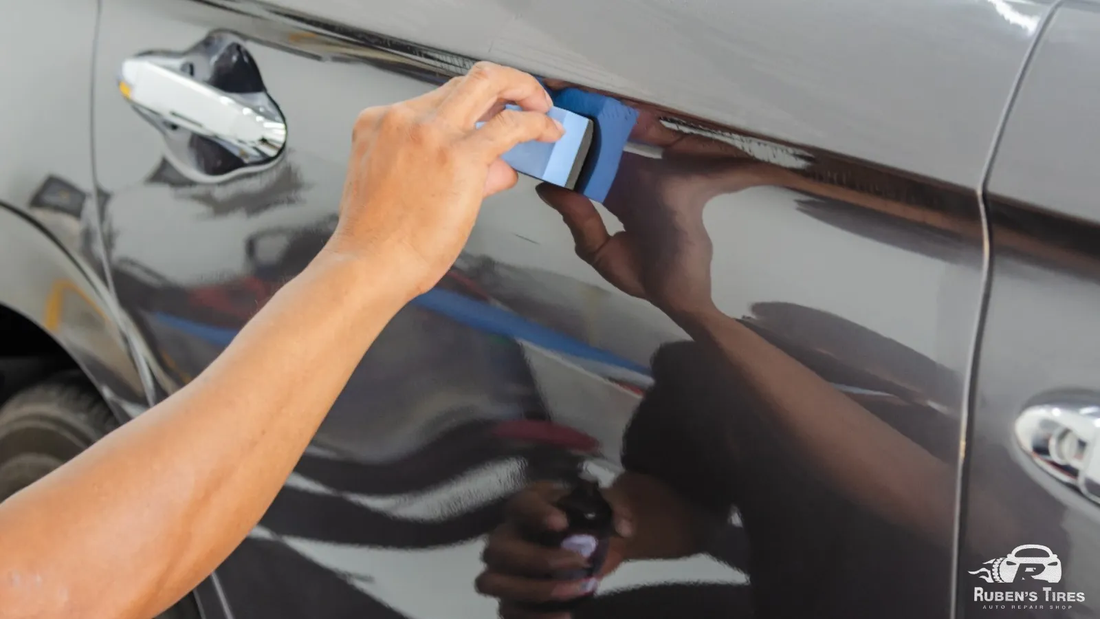 Technician using a detailing tool to remove scratches from a black car at Ruben's Tires in North Semoran.