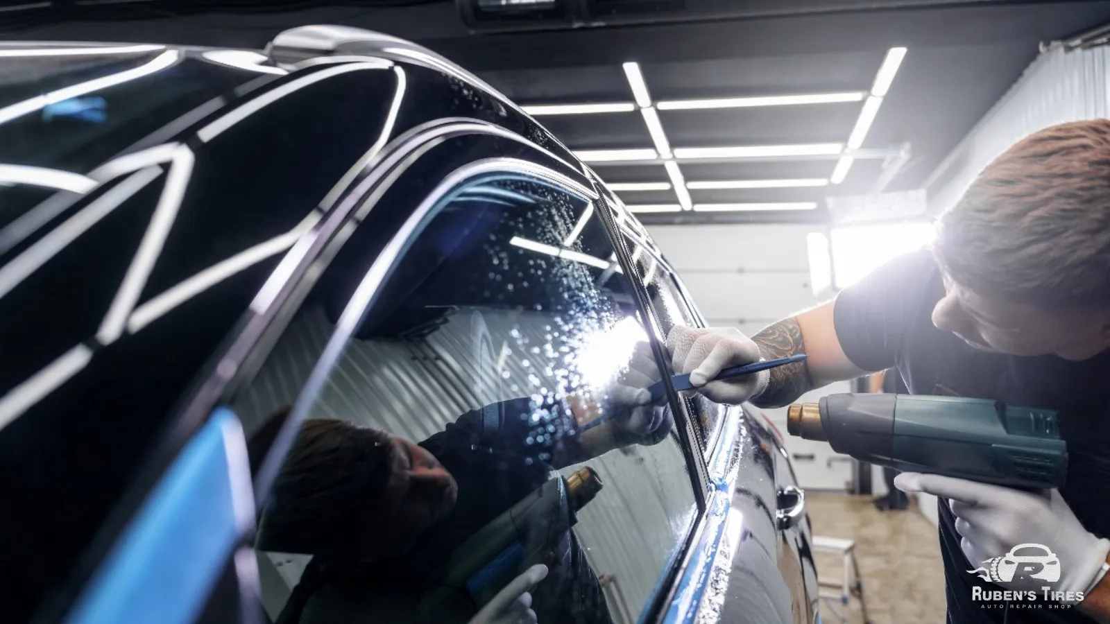 Technician installing a tinted film on a car window at Ruben's Tires in North Semoran.