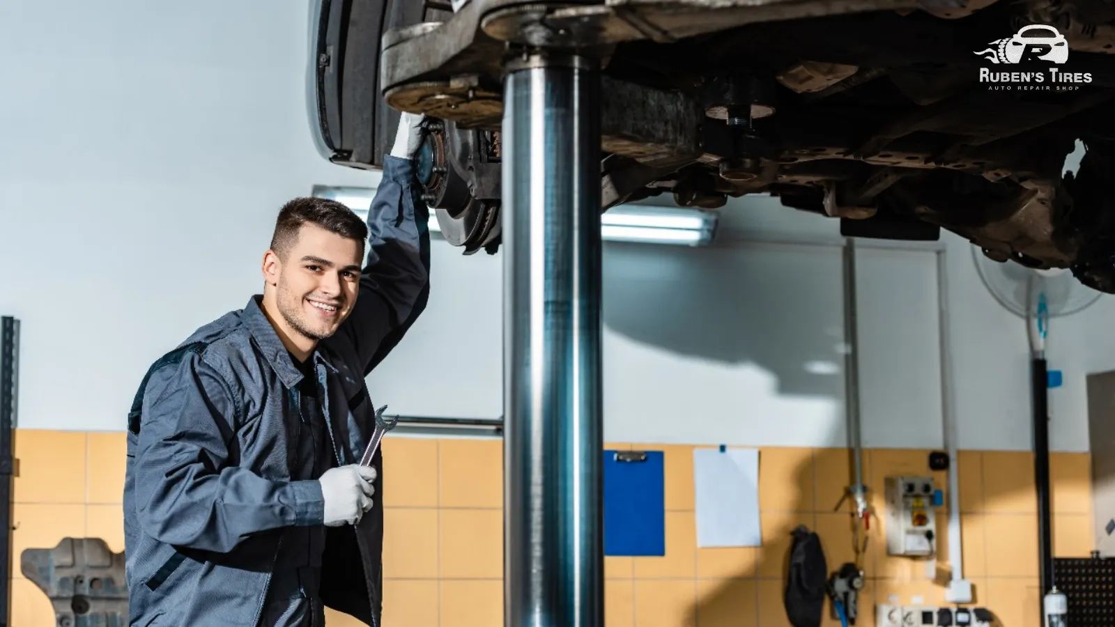 Friendly technician holding tools while servicing a vehicle's suspension in North Semoran.